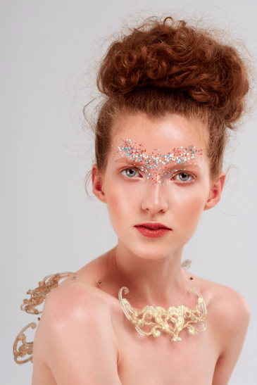 Artystyczny makijaż beauty z kolorowym brokatem wokół oczu i wysokim upięciem włosów