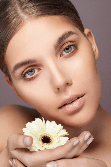 Naturalny makijaż beauty modelki trzymającej jasny kwiat
